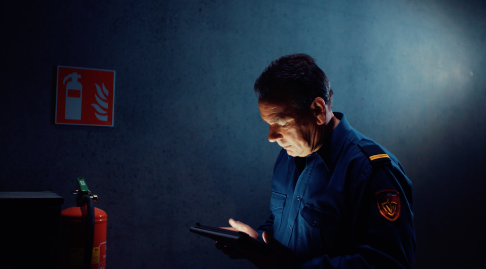 brandweerman in blauw uniform achter ipad in schemerig pand