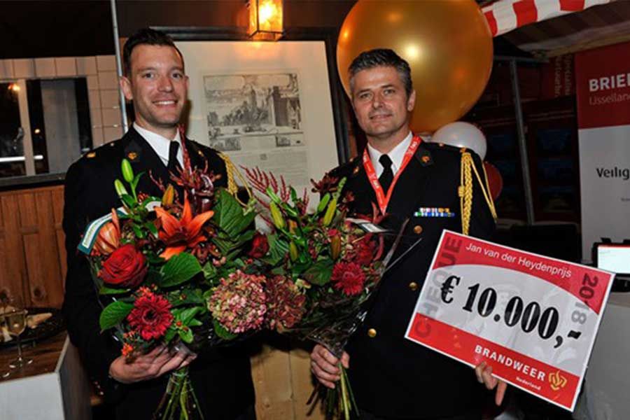 twee brandweermannen met bloemen en voucher 10.000 euro in de hand