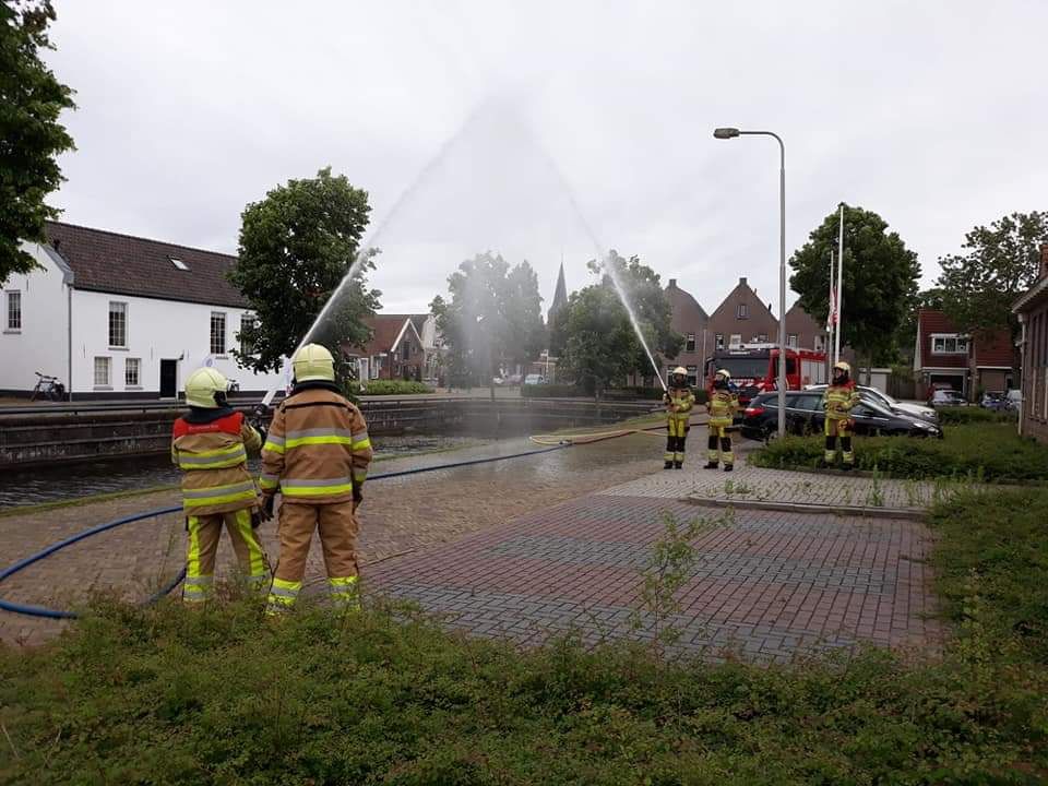 ereboog met blusslang door brandweermannen