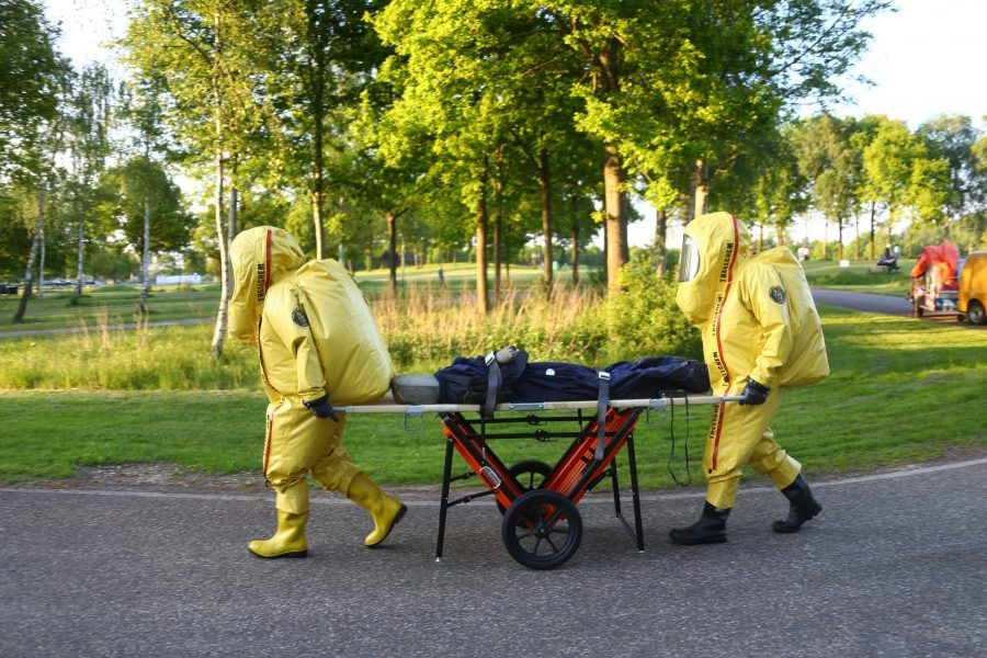 twee personen in gaspak vervoeren slachtoffer