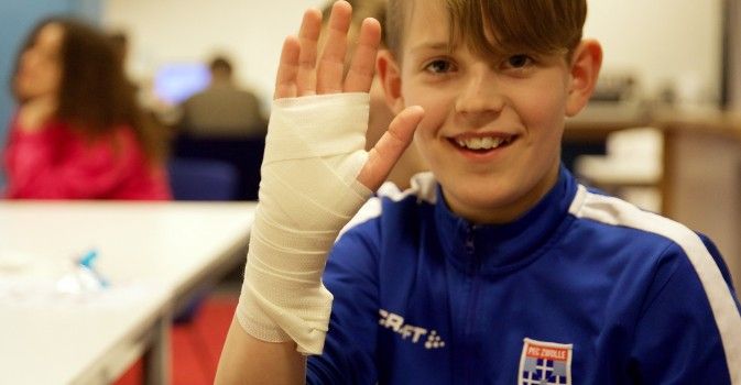 jongen in PEC voetbal shirt met hand in verband