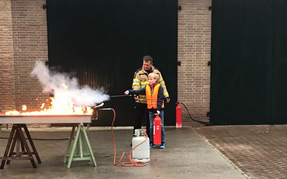 kind blust onder begeleiding brandweerman vuurbak