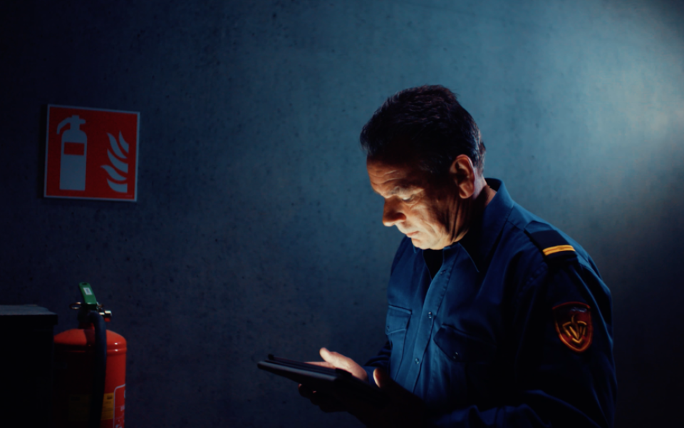 brandweerman in blauw uniform achter ipad in schemerig pand