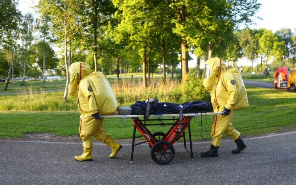 twee personen in gaspak vervoeren slachtoffer