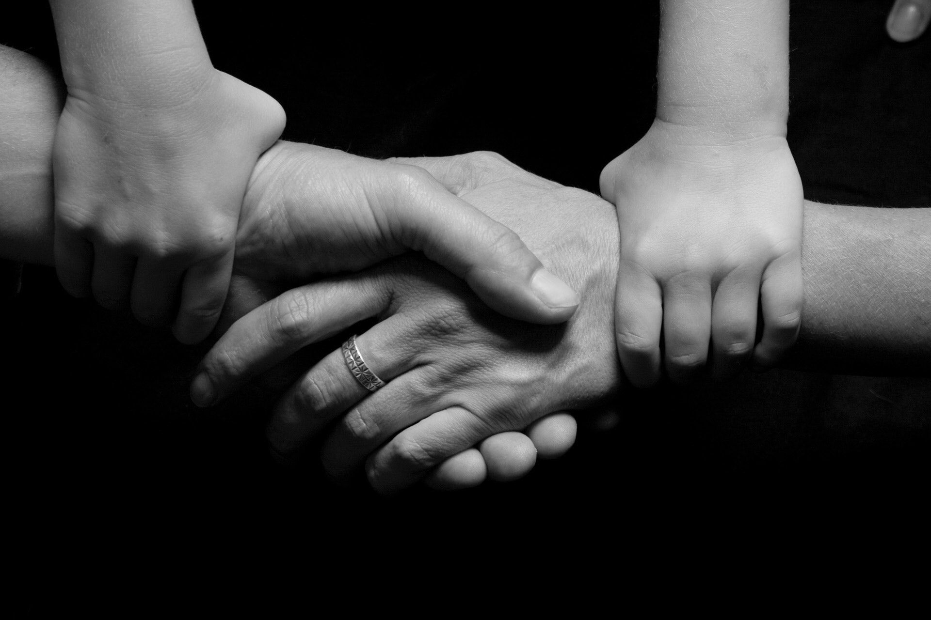 twee handen schudden elkaar en kinderhanden erboven