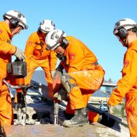 vier mannen in oranje pakken met specialistisch werk bezig