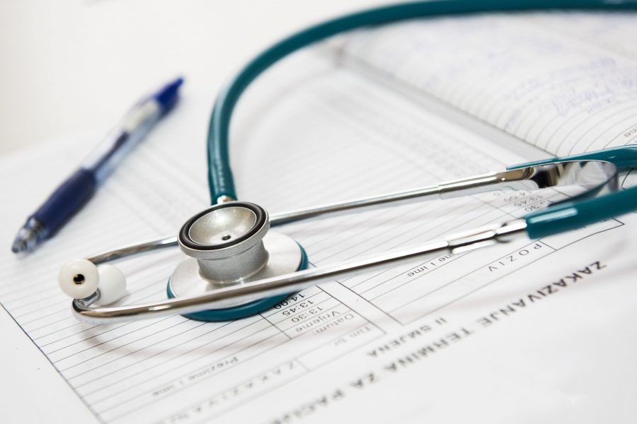 dokterspullen blauwe stetoscope en pen liggend op een memoblaadje