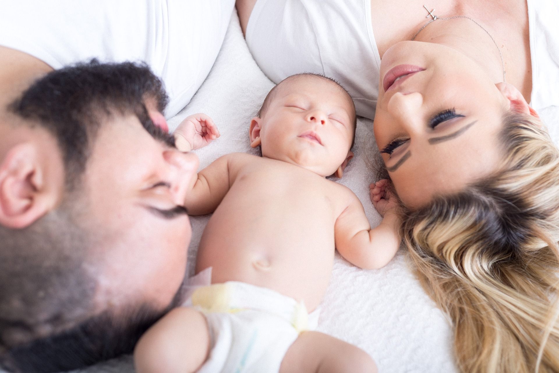 baby op bed tussen gezicht papa en mama