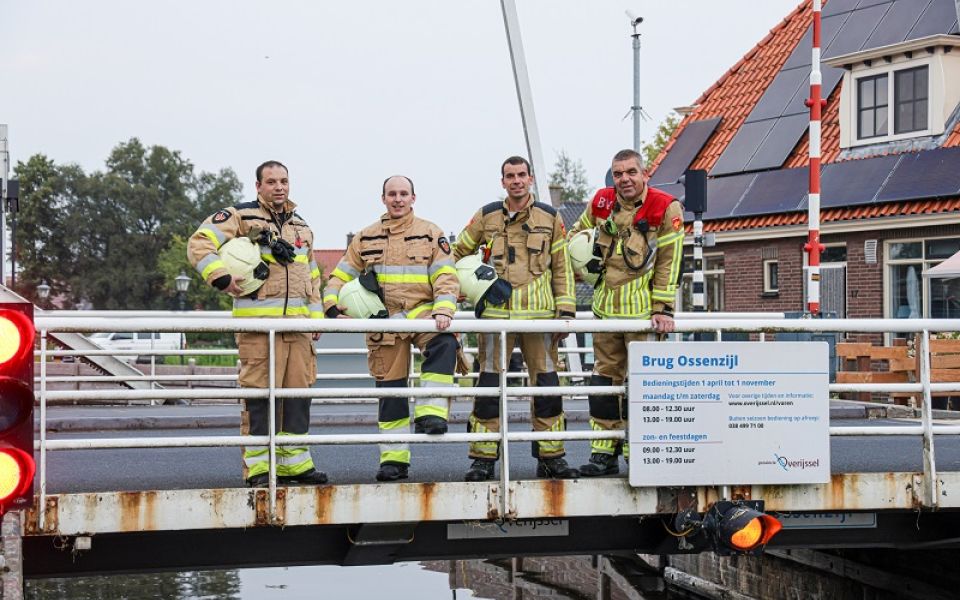 vier brandweermannen op een brug