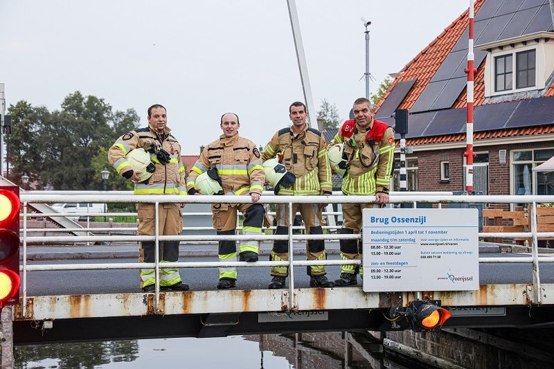 vier brandweermannen op een brug