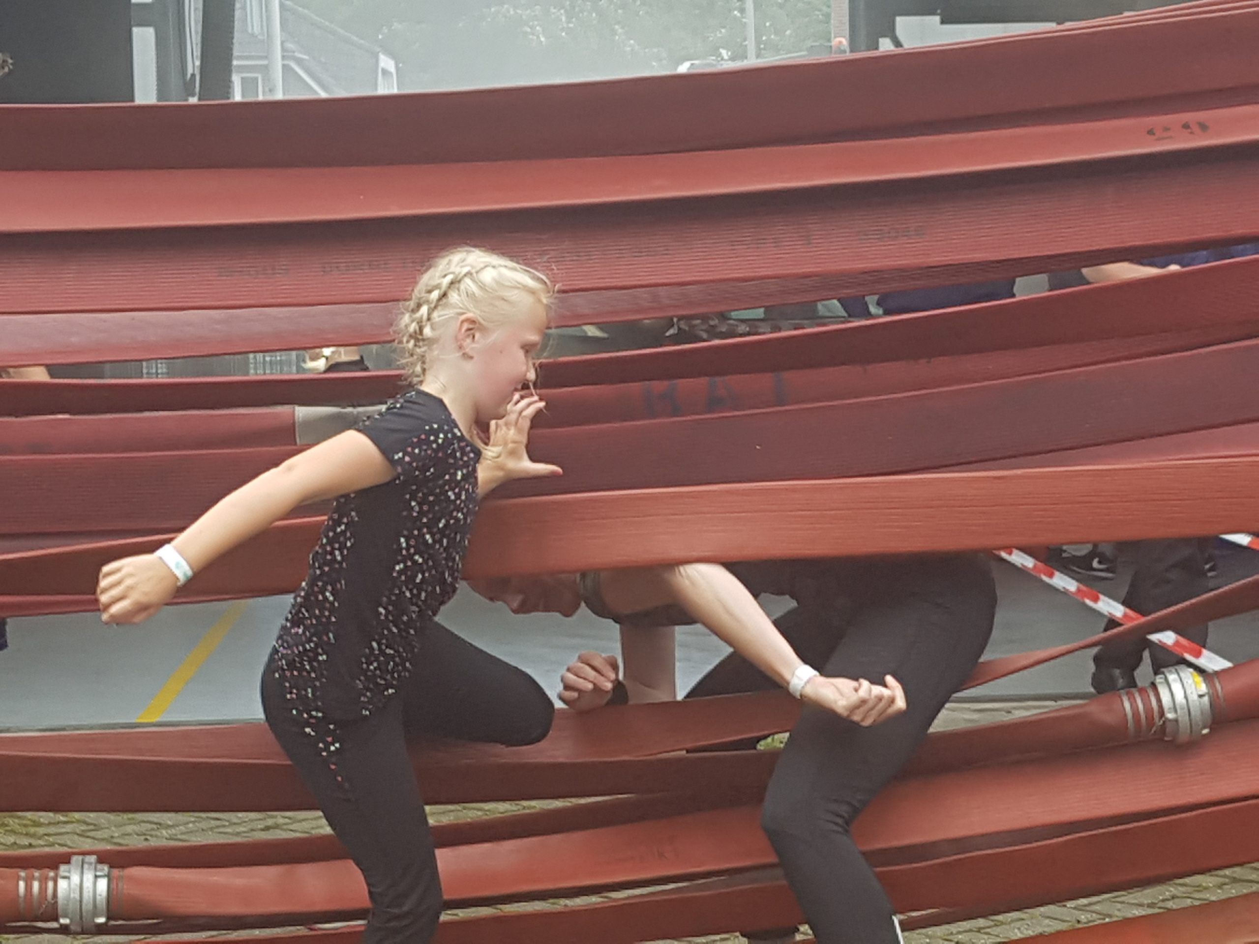 kinderen klimmen door brandweer slangen