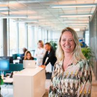Communicatiecollega in beeld. Collega's daarachter in overleg